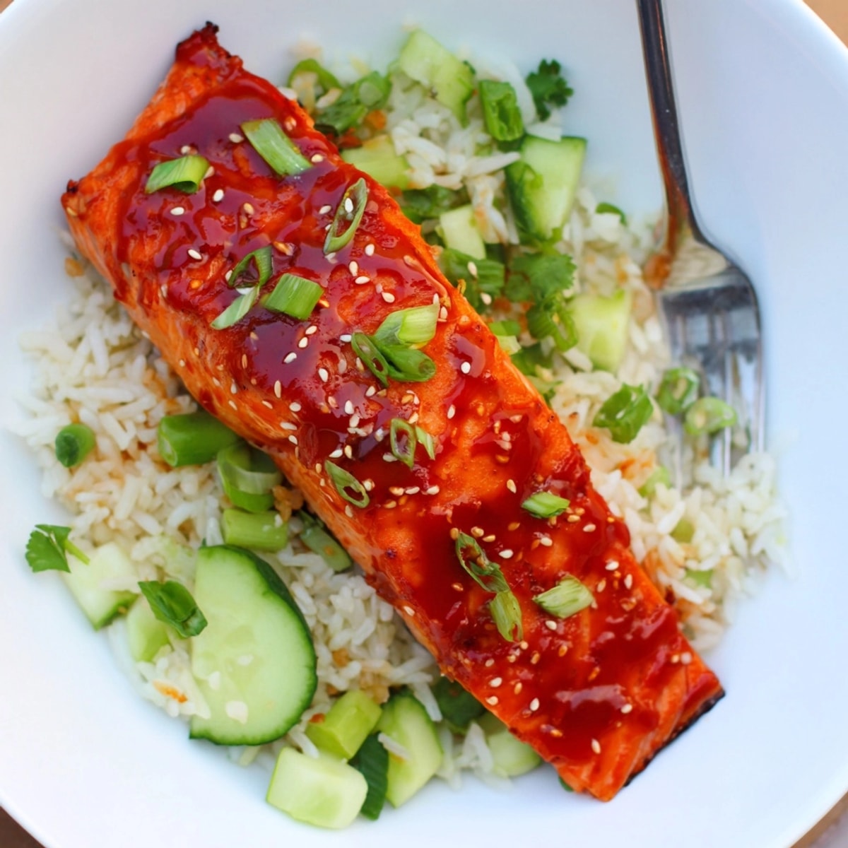 Bright Sriracha Glazed Salmon Recipe over Jasmine rice with diced cucumbers and vibrant green onions.