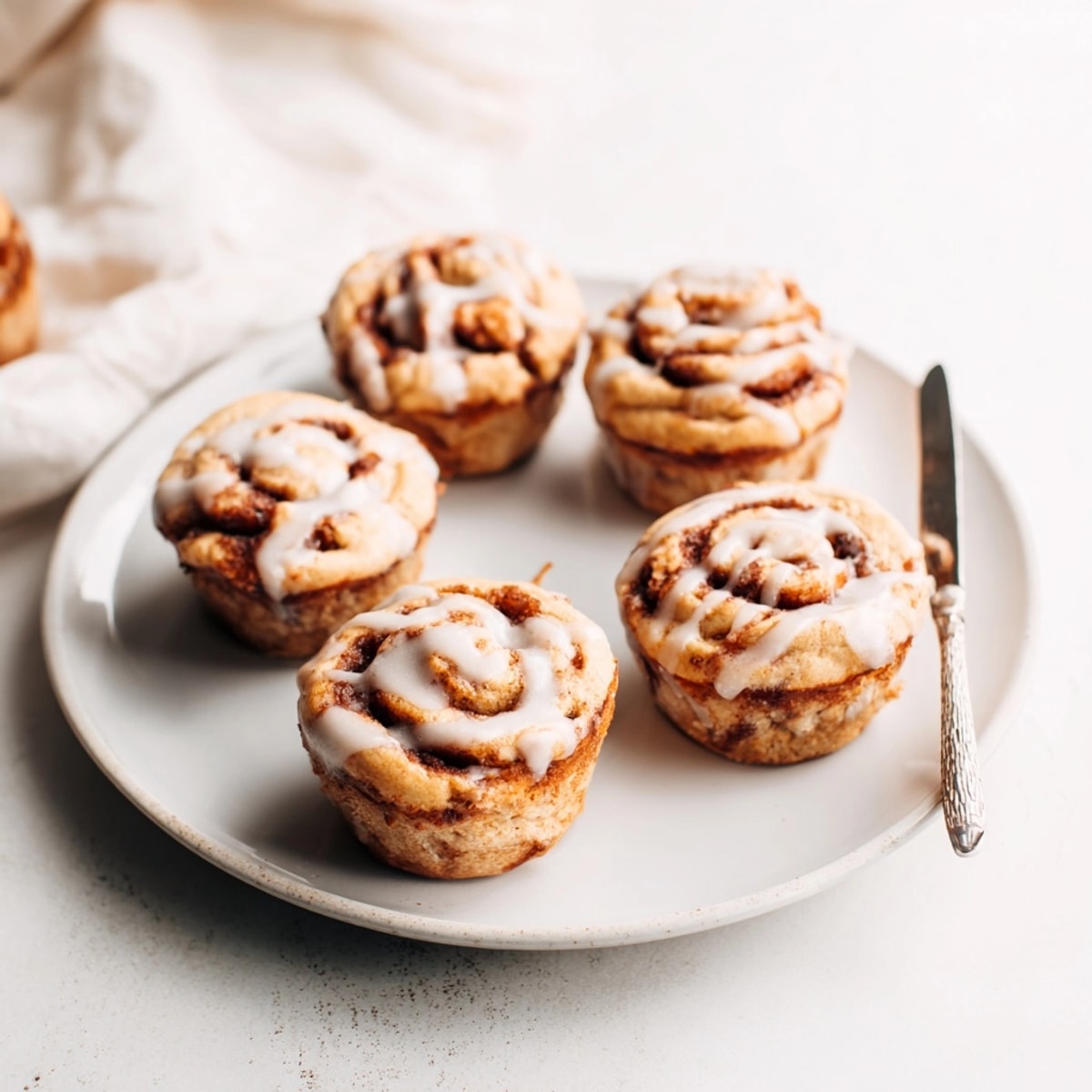 Fluffy Cinnamon Roll Protein Muffins with sweet cinnamon swirls baking in paper-lined muffin tin.