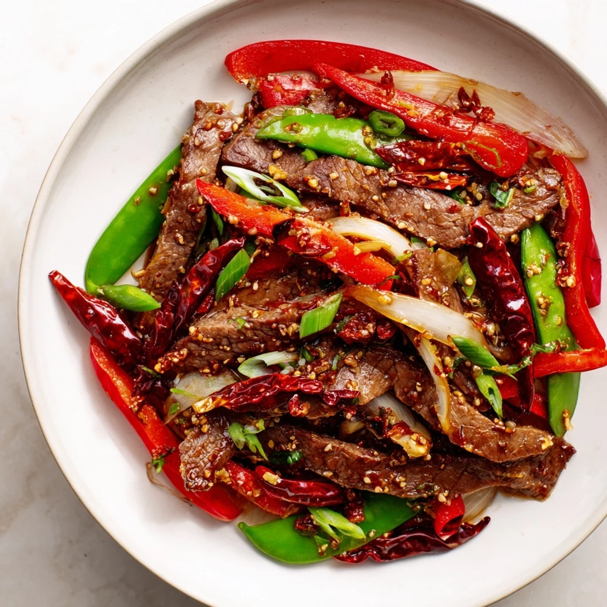 Plate of Spicy Szechuan Beef Stir Fry: a vibrant mix of beef and vegetables glistening with sauce.
