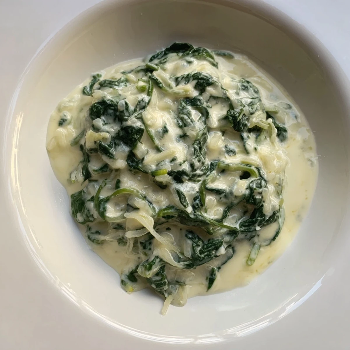 Creamy spinach served warm, featuring vibrant green spinach in a smooth, cheesy sauce.