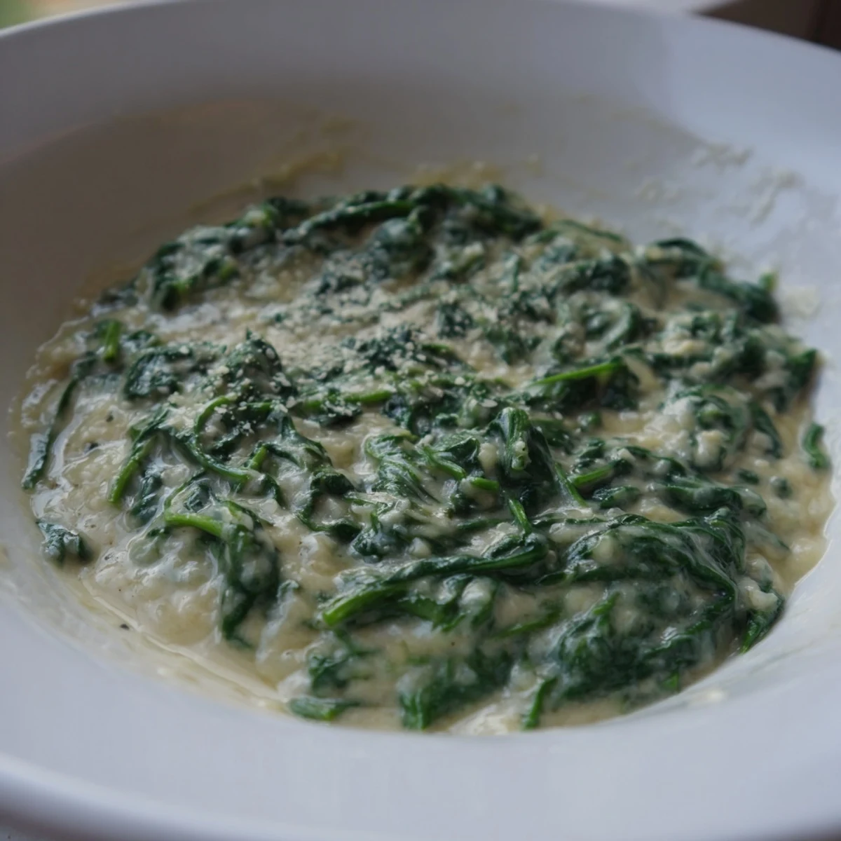 A close-up of creamy spinach, with visible Parmesan cheese and the scent of garlic and nutmeg.