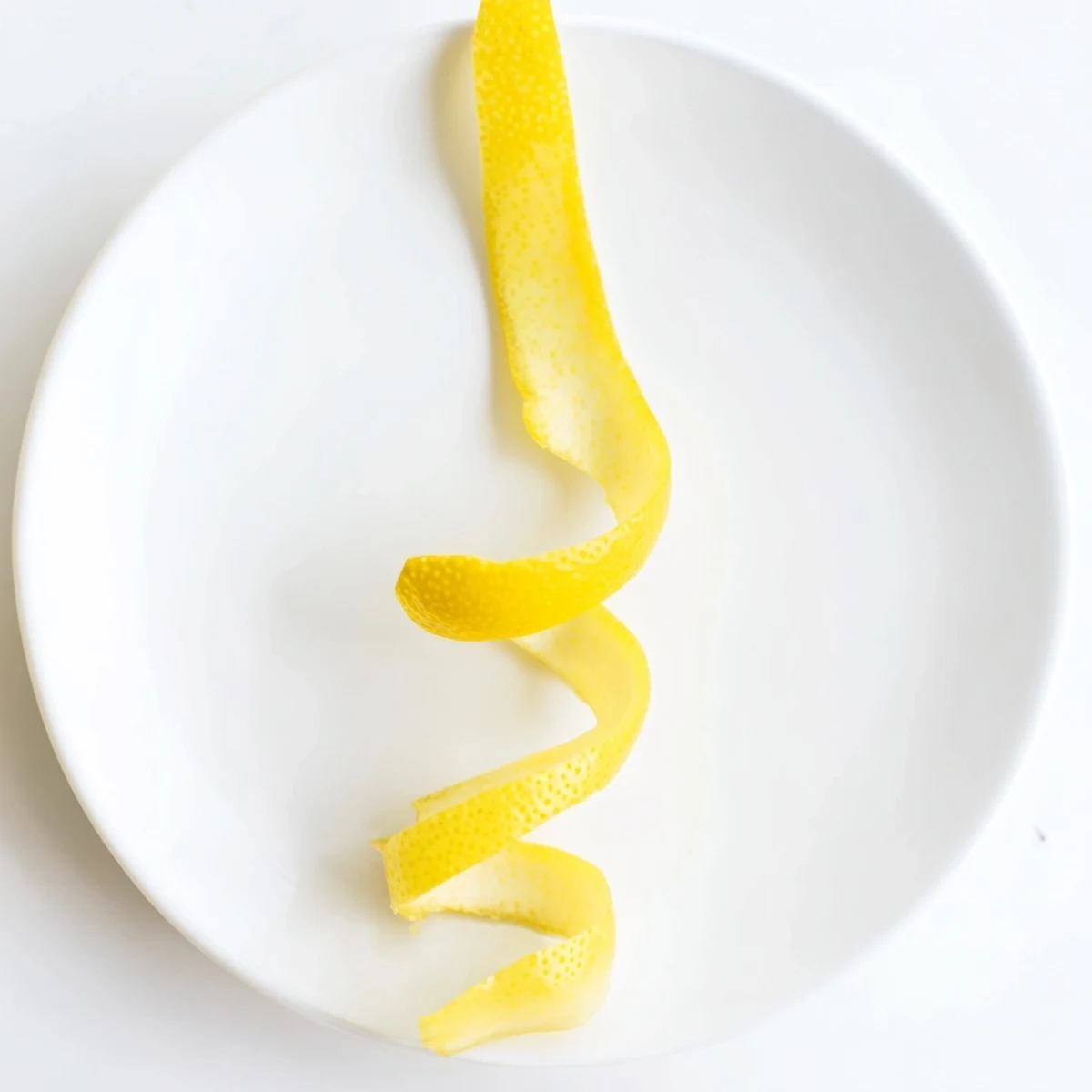 Fresh lemon twist garnish, coiled elegantly, ready to add bright citrus fragrance to a cocktail.