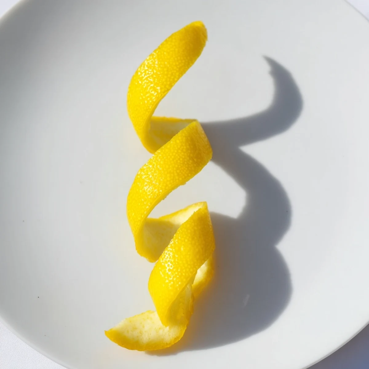 Vibrant yellow lemon twist garnish, spiraled against a dark cocktail, hinting at a tangy flavor.