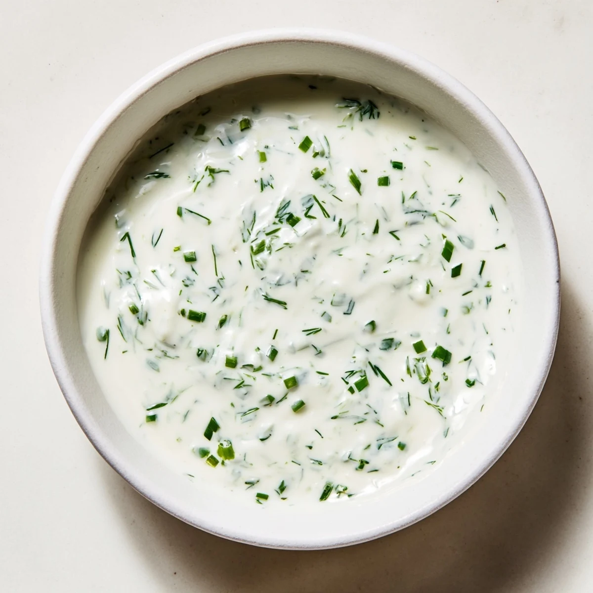 A vibrant close-up of creamy ranch dressing, boasting visible fresh herbs and ready to serve.