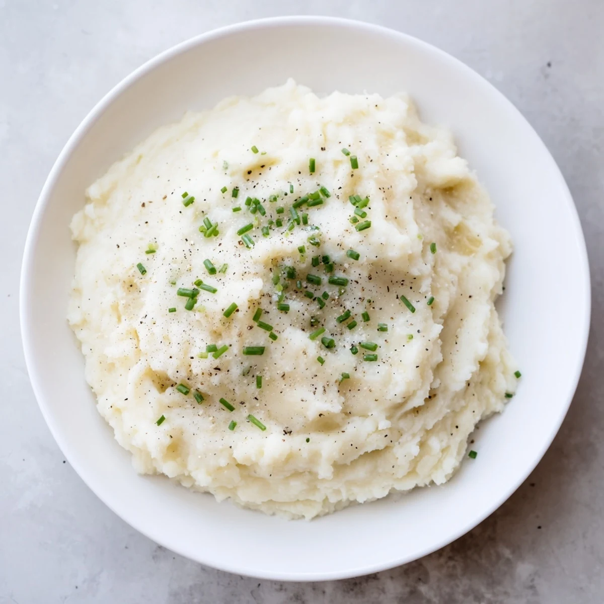 Smooth homemade mashed cauliflower, garnished with fresh chives, is a lighter, flavorful dish.