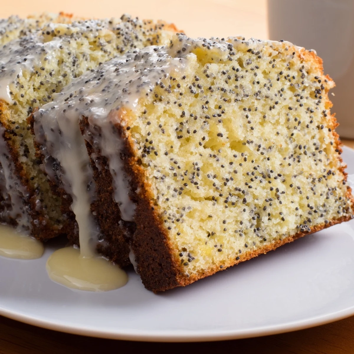 A beautifully sliced Poppy Seed Cake, showcasing the fluffy interior studded with tiny, dark seeds.