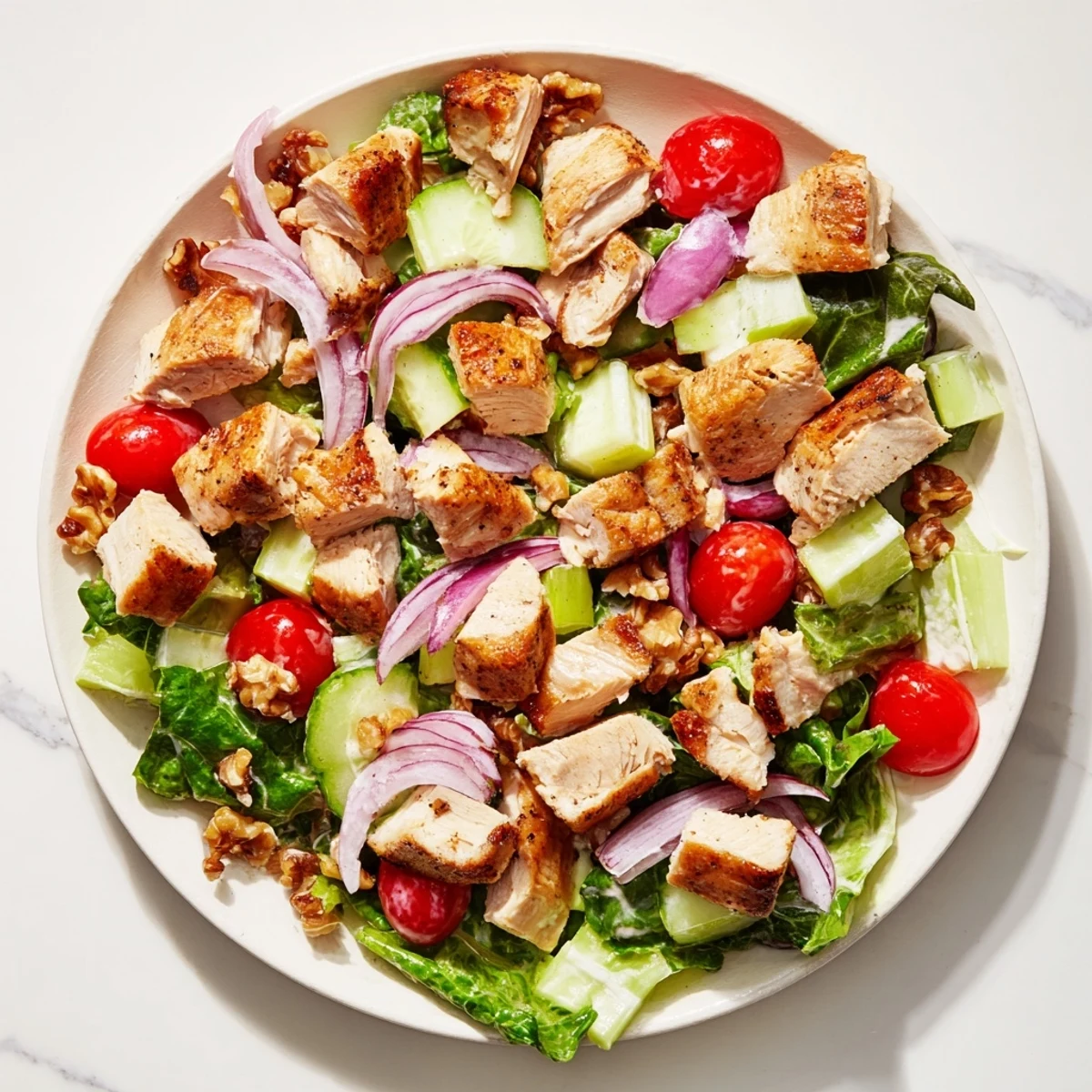 Creamy chicken salad, visible with diced celery and tomatoes, ready to be served and enjoyed.