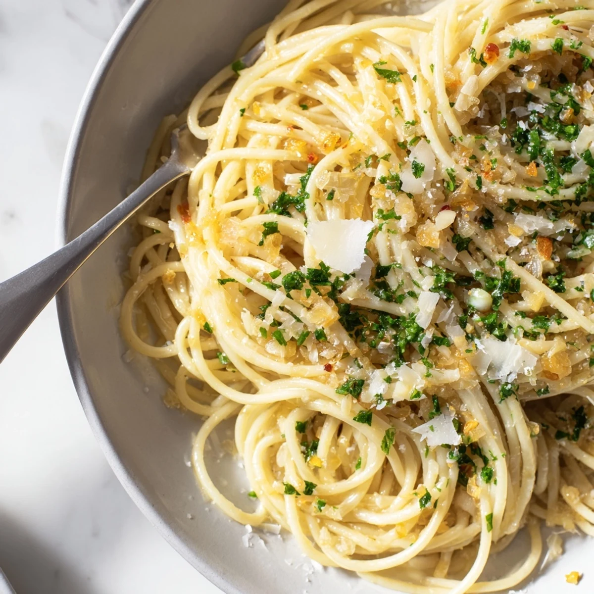 Close-up of freshly made Pasta Garlic, featuring the garlic, olive oil, and parsley in a pretty dish.