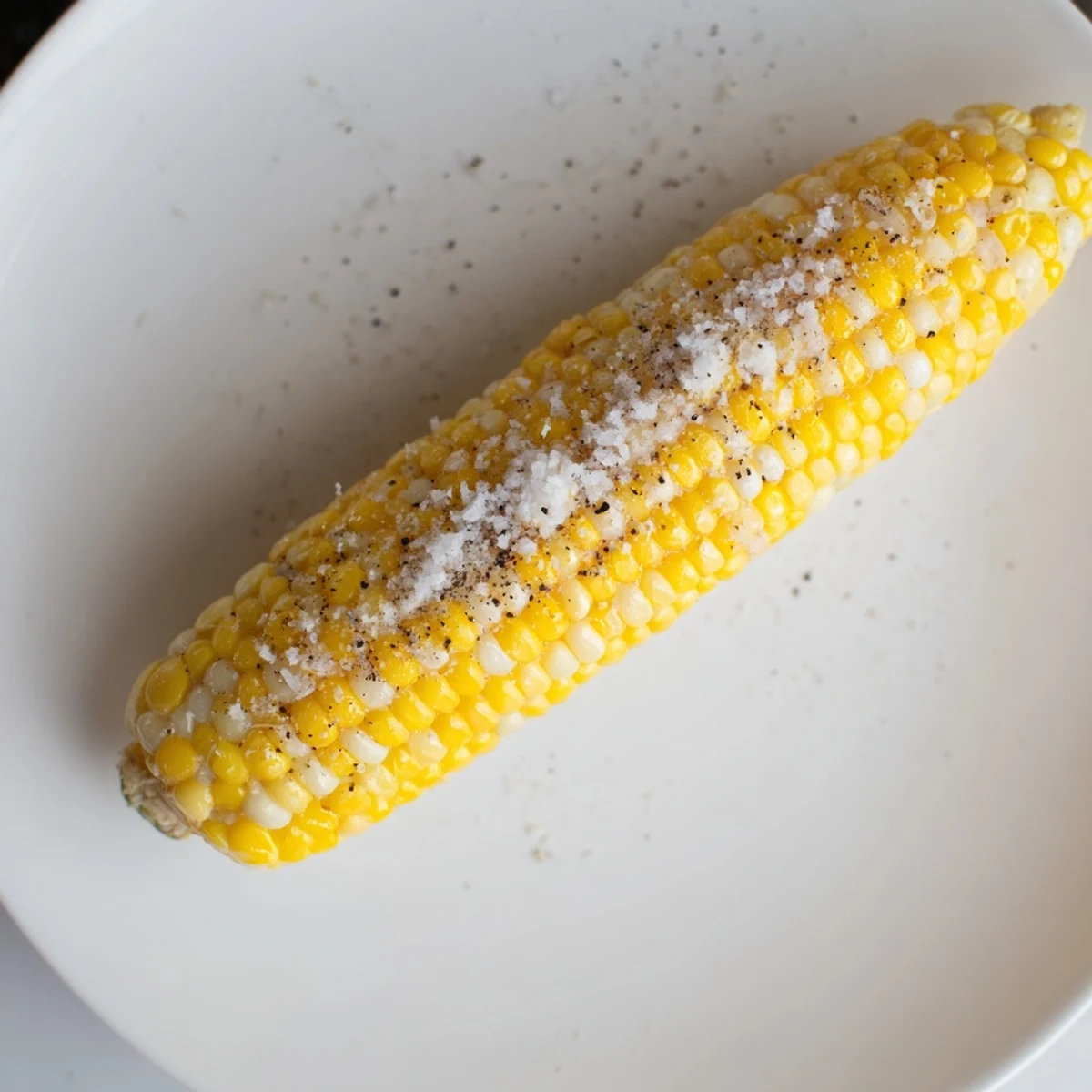 Golden corn on the cob glistening from melted butter, ready to season and savor as a summer side.