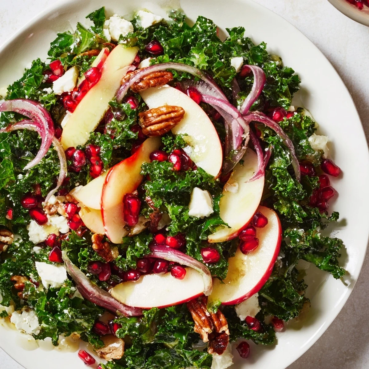 A refreshing close-up showcases a bright Winter Kale Salad with Pomegranate, ready for a healthy meal.