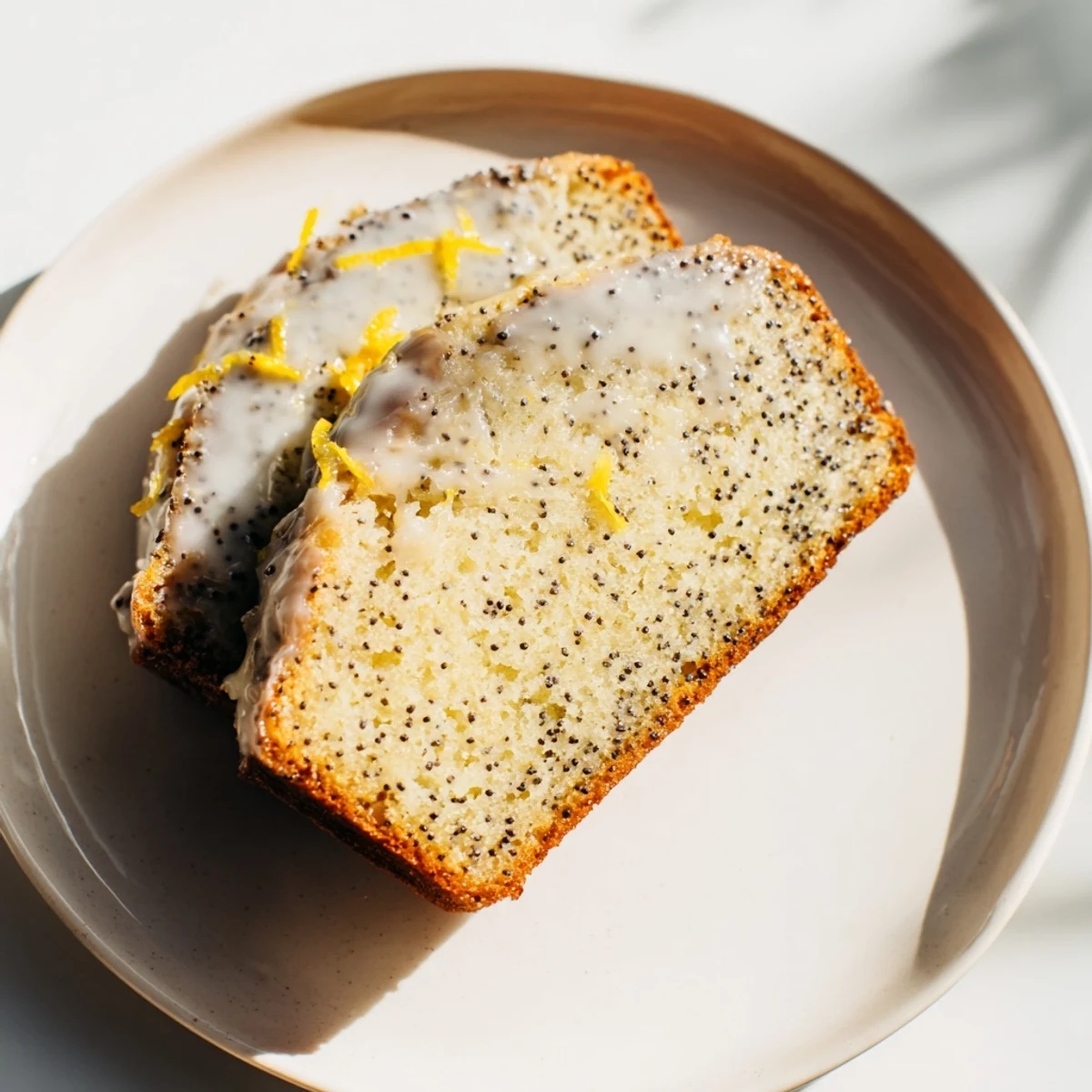 A slice of moist Lemon Poppy Seed Loaf with visible poppy seeds, ideal alongside morning coffee.