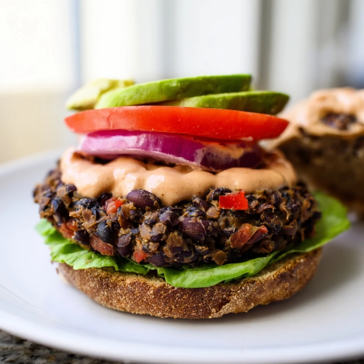 Appetizing Vegan Black Bean Burger with chipotle mayo, served with crispy baked sweet potato fries on the side.