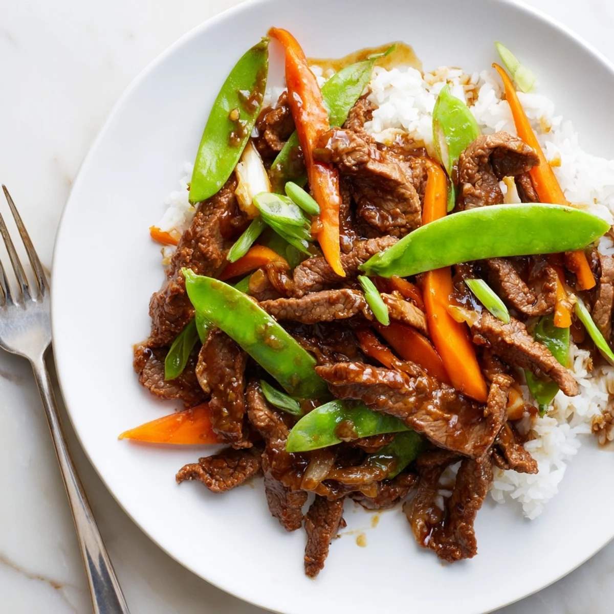 Tender strips of Beef Stir Fry with Snow Peas and Carrots garnished with fresh green onions.