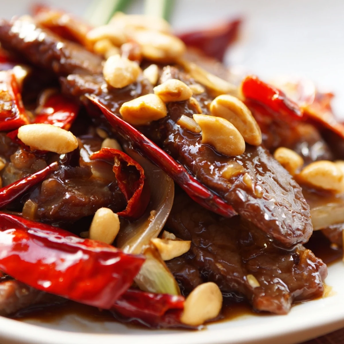 A heaping plate of Spicy Szechuan Beef with Peanuts is served alongside fluffy steamed rice.