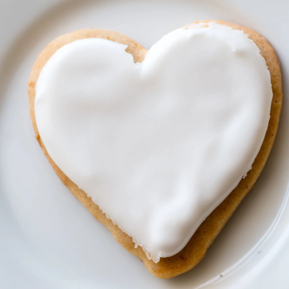 Close-up of a Heart Shaped Sugar Cookies with Royal Icing showing delicate piping details against a rustic wooden cutting board surface.