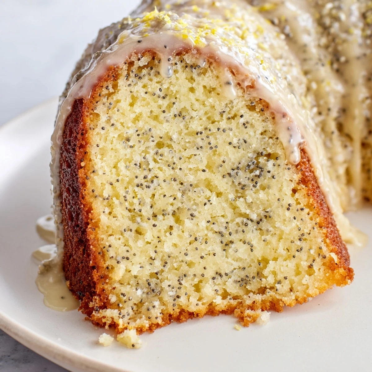 Close-up view of the moist interior of a Lemon Poppy Seed Bundt Cake, highlighting the dark poppy seeds in the golden crumb.