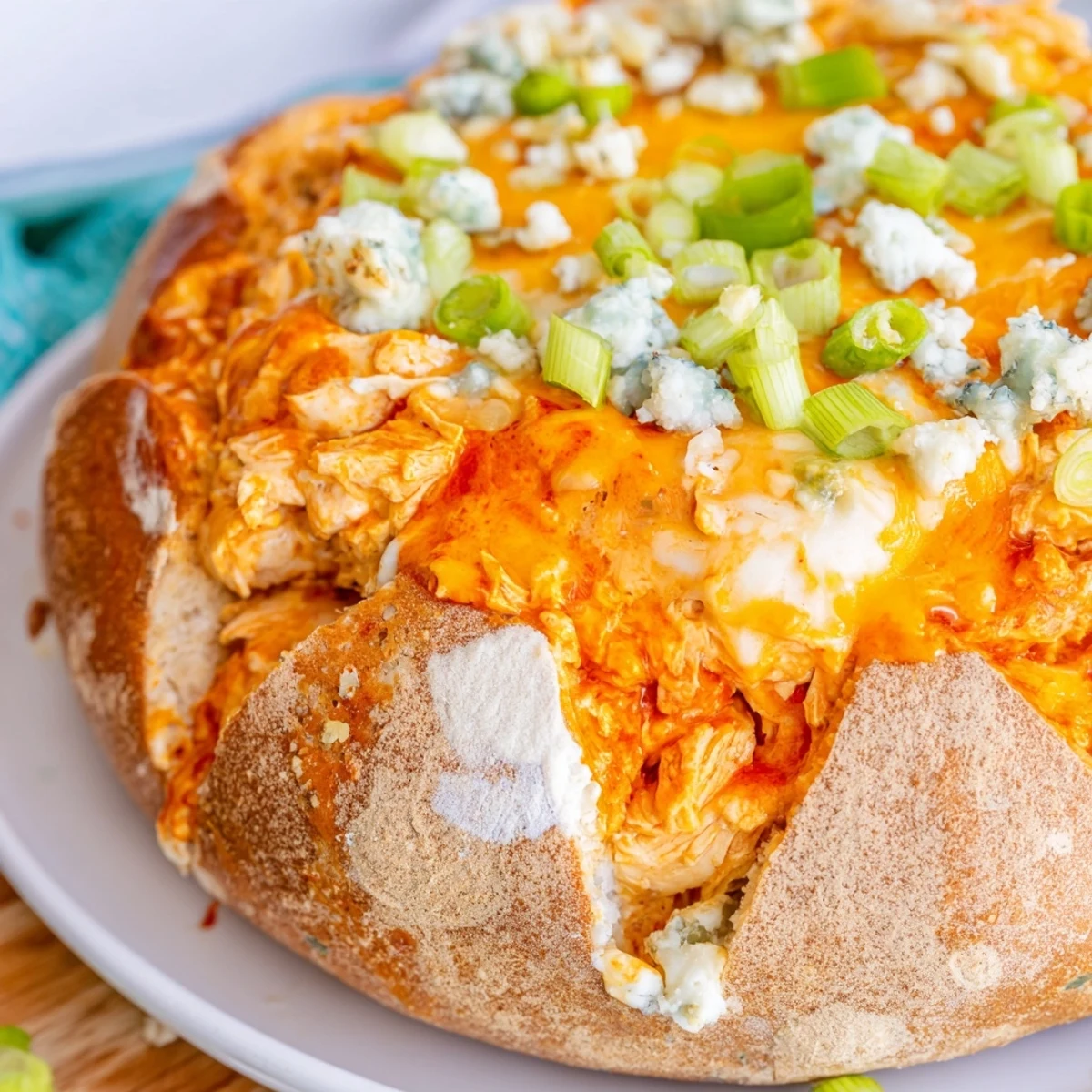 Spicy Tailgate Buffalo Chicken Dip steaming in a crusty bread bowl, surrounded by celery sticks and chips.