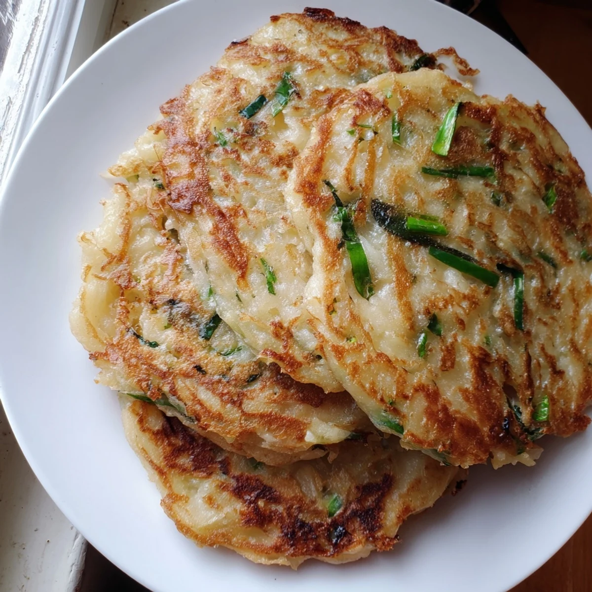 Freshly fried Irish Boxty Pancakes are served warm, topped with creamy sour cream and extra green scallions.