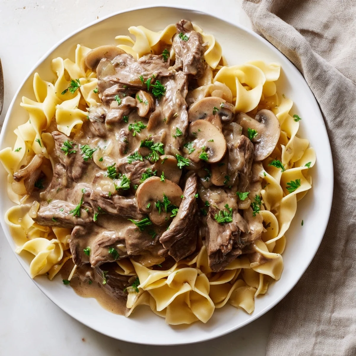 Hearty Beef Stroganoff with juicy beef and mushrooms spooned over warm buttered egg noodles.