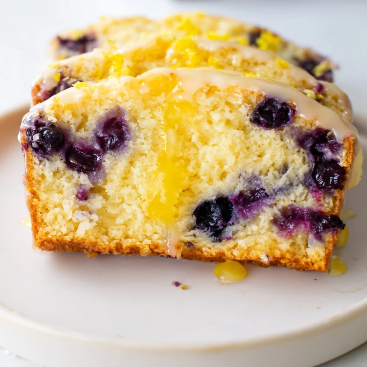 Warm Lemon Blueberry Yogurt Loaf Cake served on a plate with a fork for breakfast or dessert.