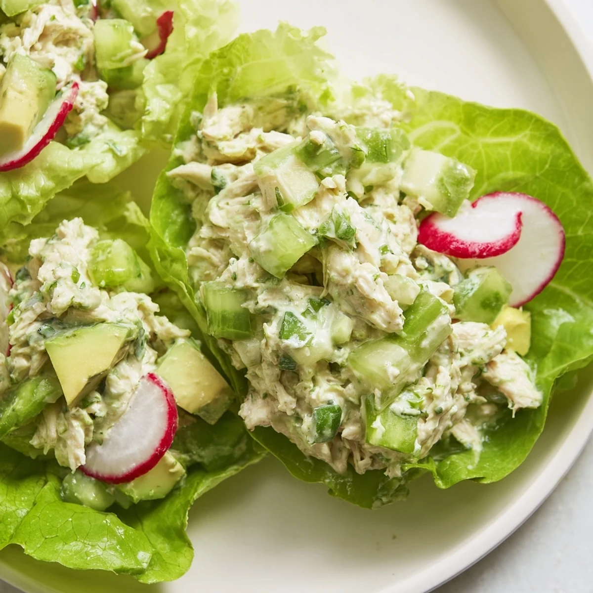 Overhead view of Green Goddess Chicken Salad Lettuce Wraps in crisp lettuce cups, showing fresh herbs and diced celery for crunch.