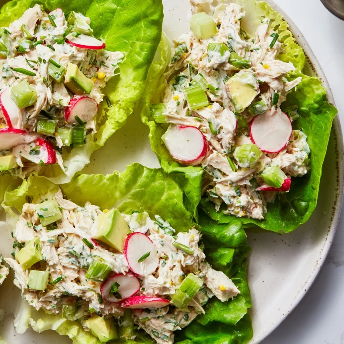 Green Goddess Chicken Salad Lettuce Wraps displayed on a white platter with microgreens garnish and bright lemon wedges nearby.