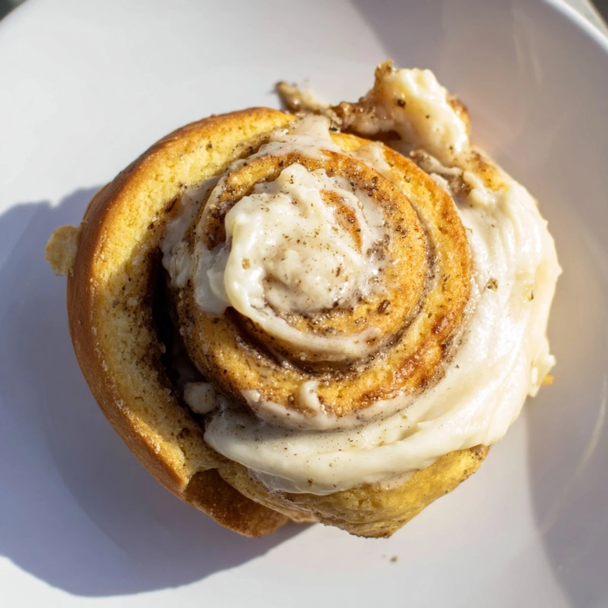 A close-up view of fluffy Keto Cinnamon Buns with cinnamon sugar filling and creamy vanilla icing drizzled on top.