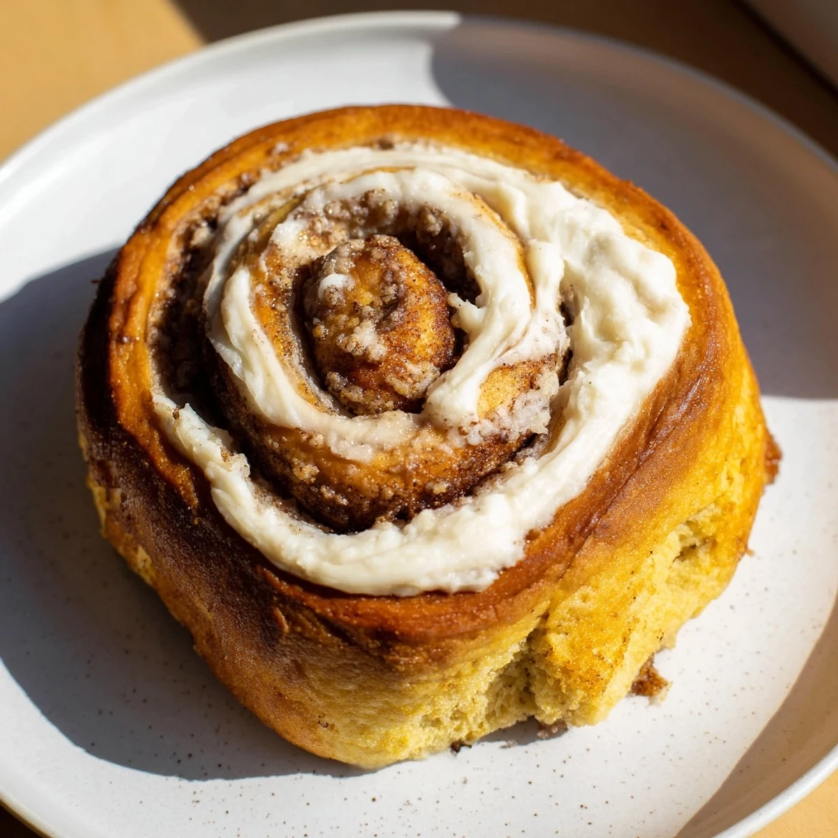 Freshly baked Keto Cinnamon Buns with a glossy cream cheese icing swirl, served warm on a rustic wooden board.