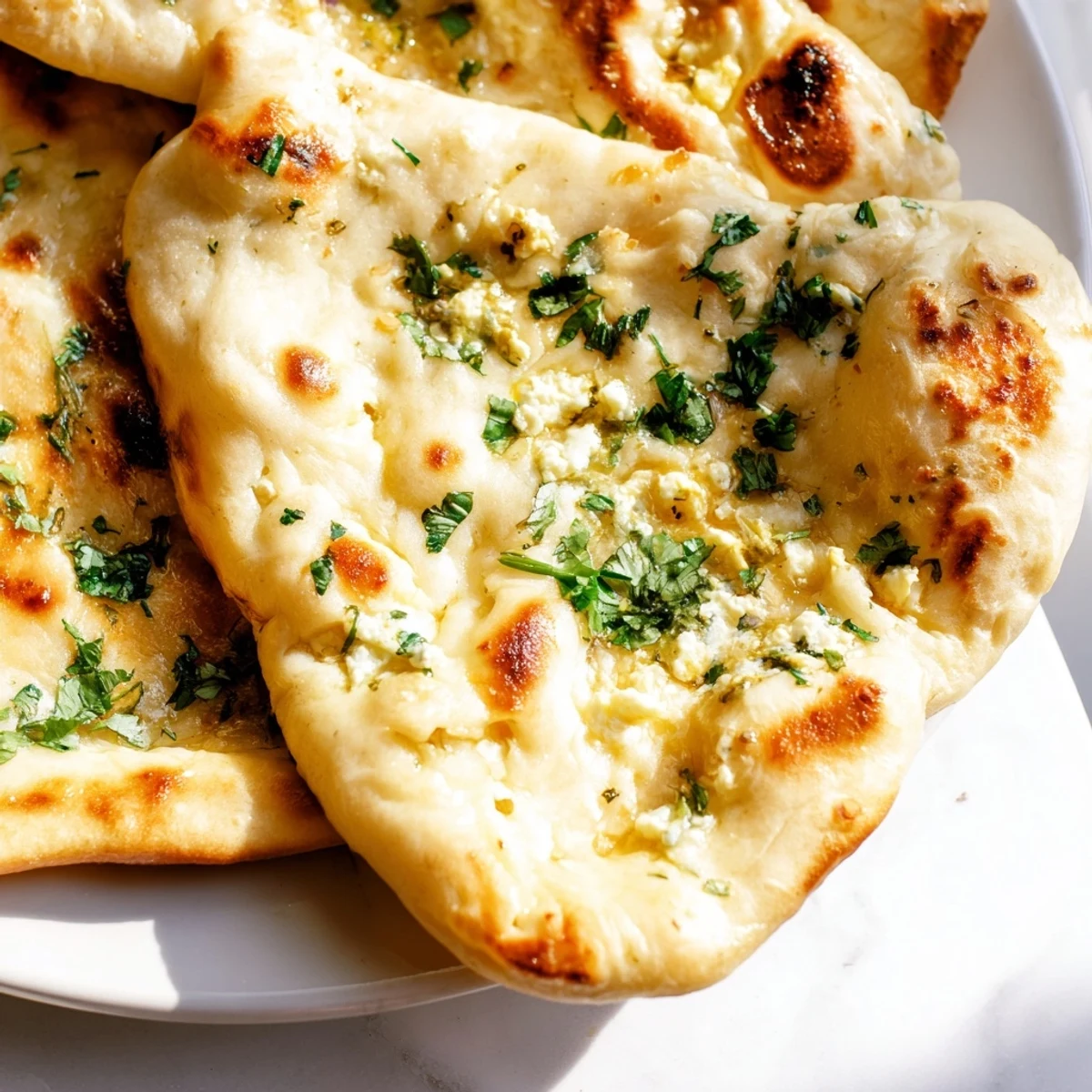 Soft, pillowy Cottage Cheese Garlic Naan stacked on a wooden board, revealing a creamy cottage cheese filling inside.