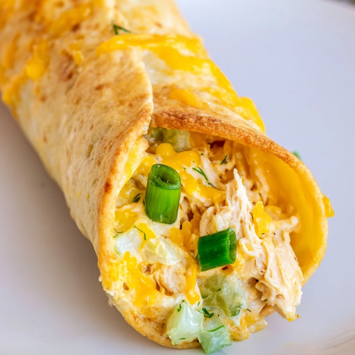 Golden brown Dill Pickle Ranch Chicken Taquitos sit on a baking sheet, showing crispy tortilla edges and melted cheddar cheese.