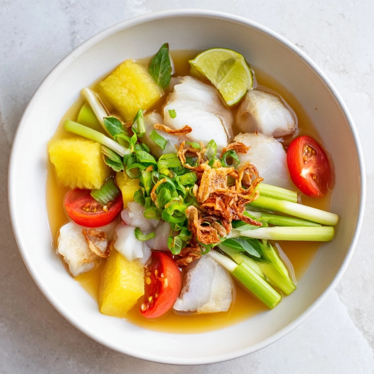 Close-up on a ladle lifting tender fish and pineapple from a pot of bright red-orange Modern Canh Chua. The tangy broth glistens, with cilantro and scallions adding a pop of green, perfect for a refreshing meal.