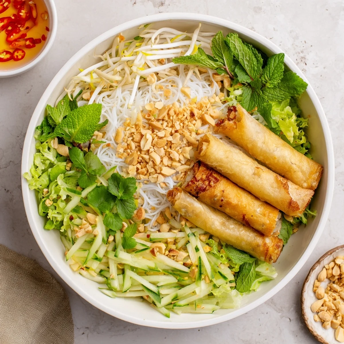 Warm Bun Cha Gio noodle bowl topped with fresh mint, cilantro, and Thai basil, drizzled with savory Vietnamese dipping sauce.