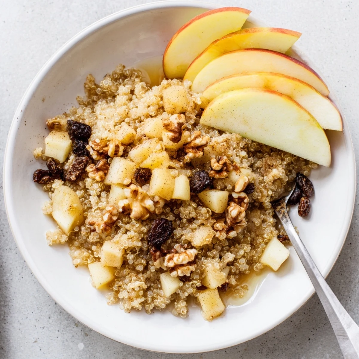 Warm, fragrant bowl of Healthy Quinoa Apple Breakfast topped with crunchy walnuts and fresh apple slices, perfect for cozy mornings.