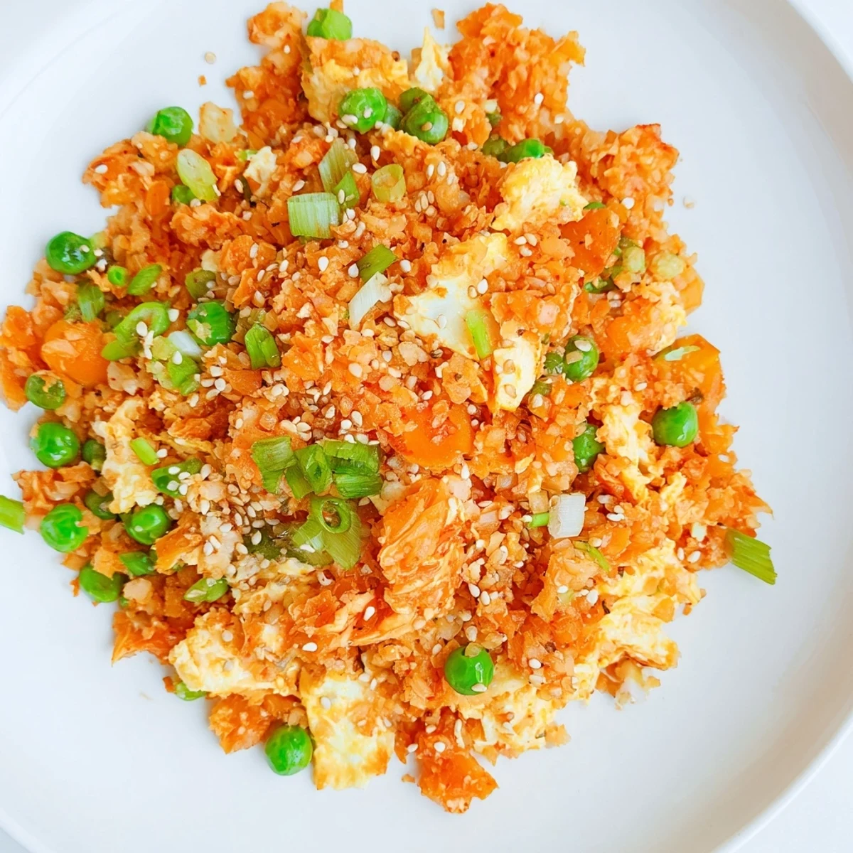 Healthy cauliflower fried rice with kimchi and eggs, topped with sesame seeds and served in a white ceramic bowl.