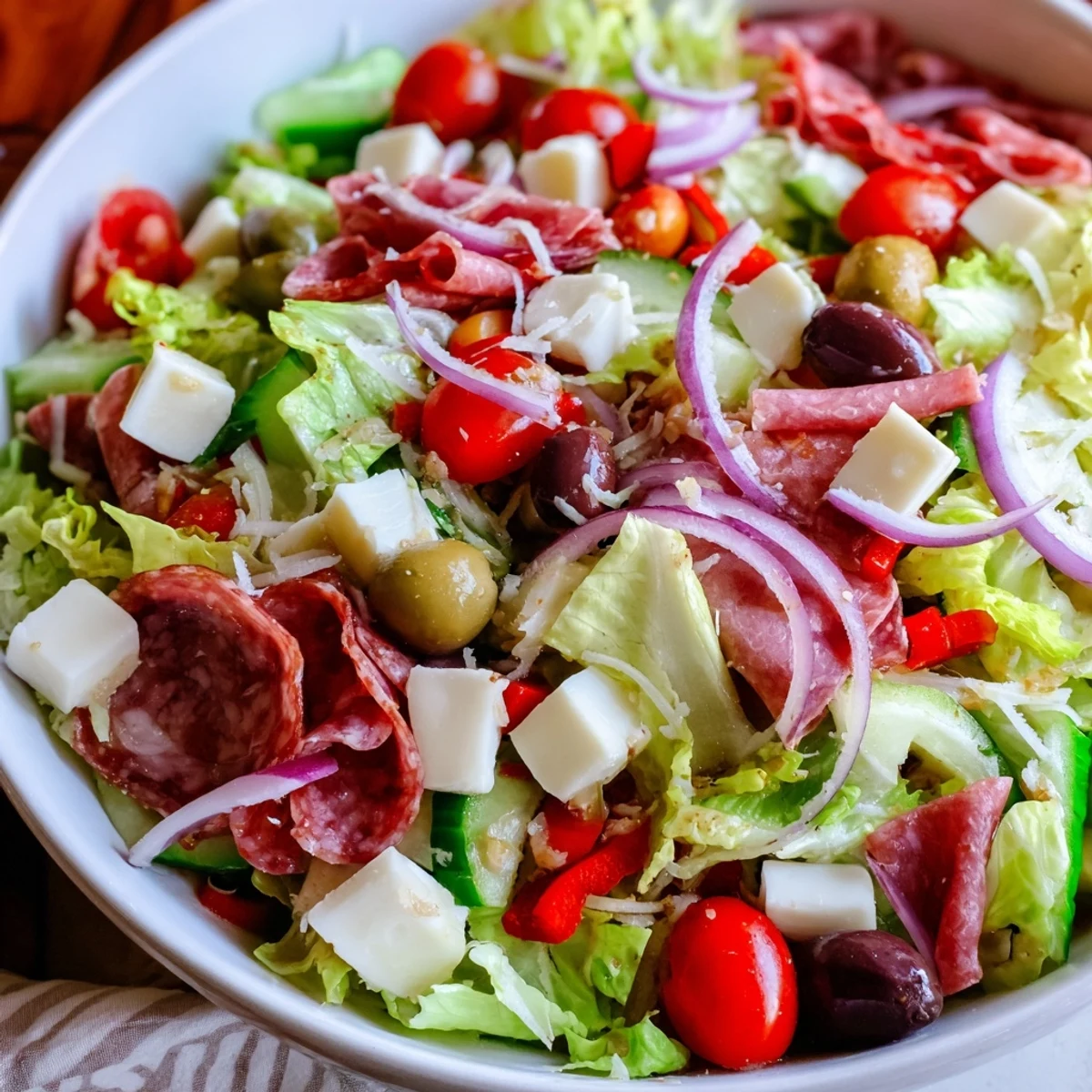 Vibrant chopped salad featuring romaine, tomatoes, olives, and pepperoncini drizzled with tangy Italian dressing