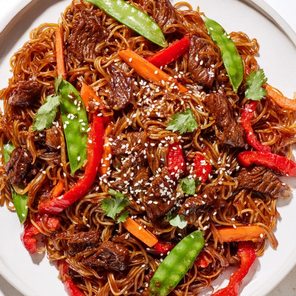 Glossy sticky beef noodles with tender steak strips and colorful vegetables coated in sweet-savory sauce