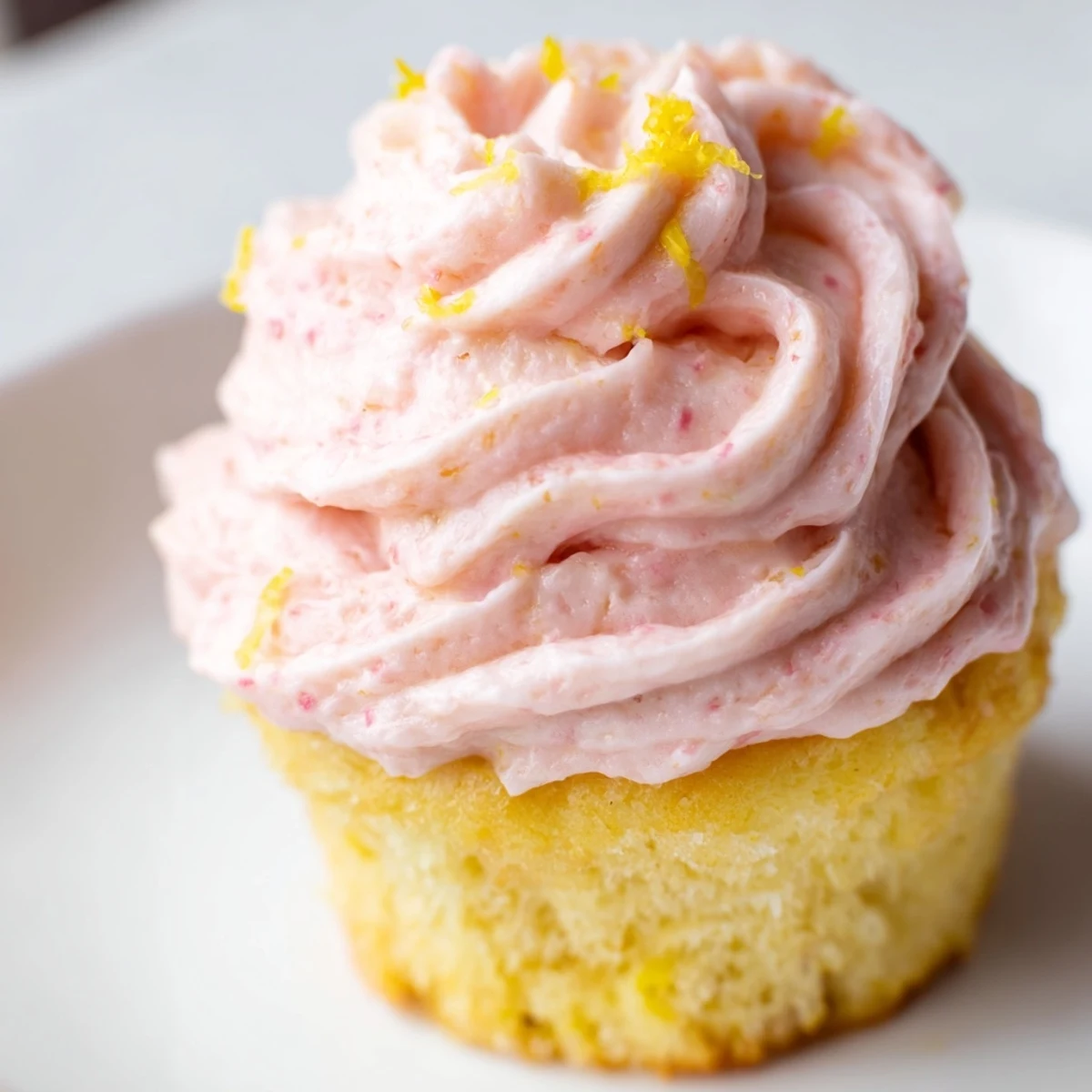 Fluffy lemon cupcakes with strawberry buttercream frosting topped with fresh strawberry slices
