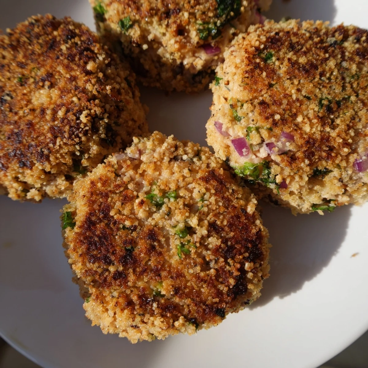 Golden brown crispy tuna cakes served on a white plate with fresh lemon wedges and parsley garnish