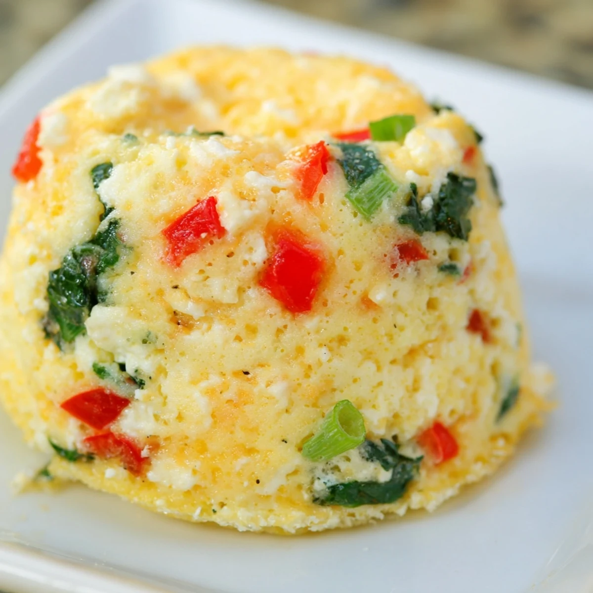 Protein-rich cottage cheese egg bites featuring cheddar, spinach, and red bell pepper pieces