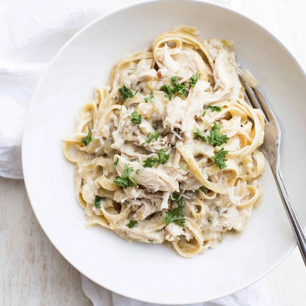 Golden slow cooker Chicken Alfredo pasta dish featuring shredded chicken breast in rich white cream sauce over al dente fettuccine