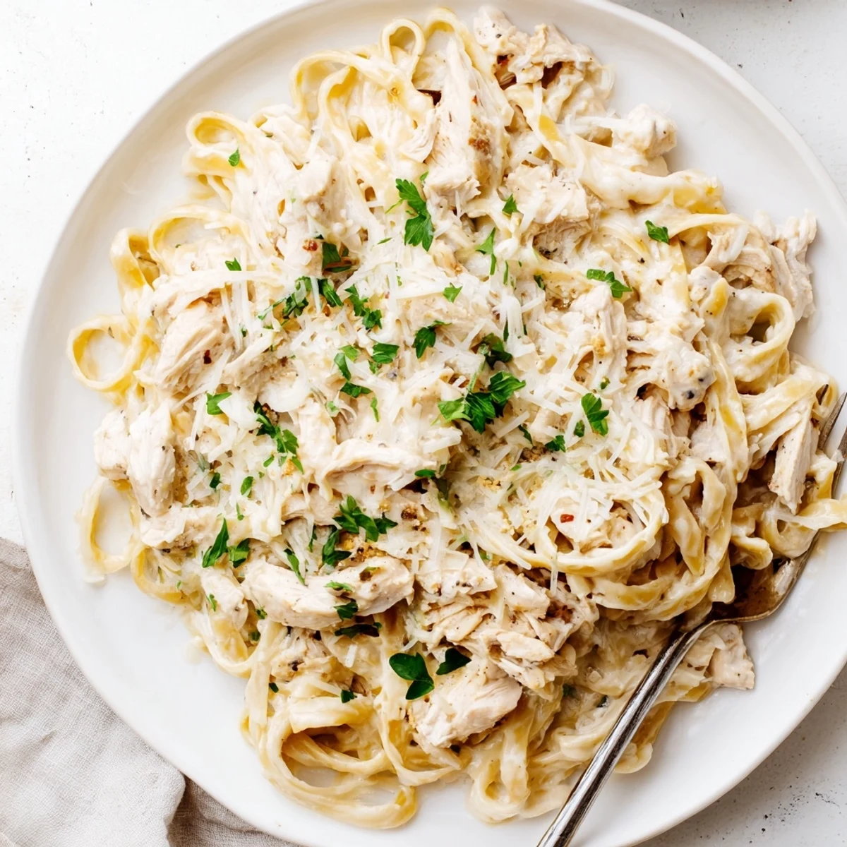 Homemade Crock Pot Chicken Alfredo served family style with steaming pasta coating in velvety garlic parmesan cream sauce