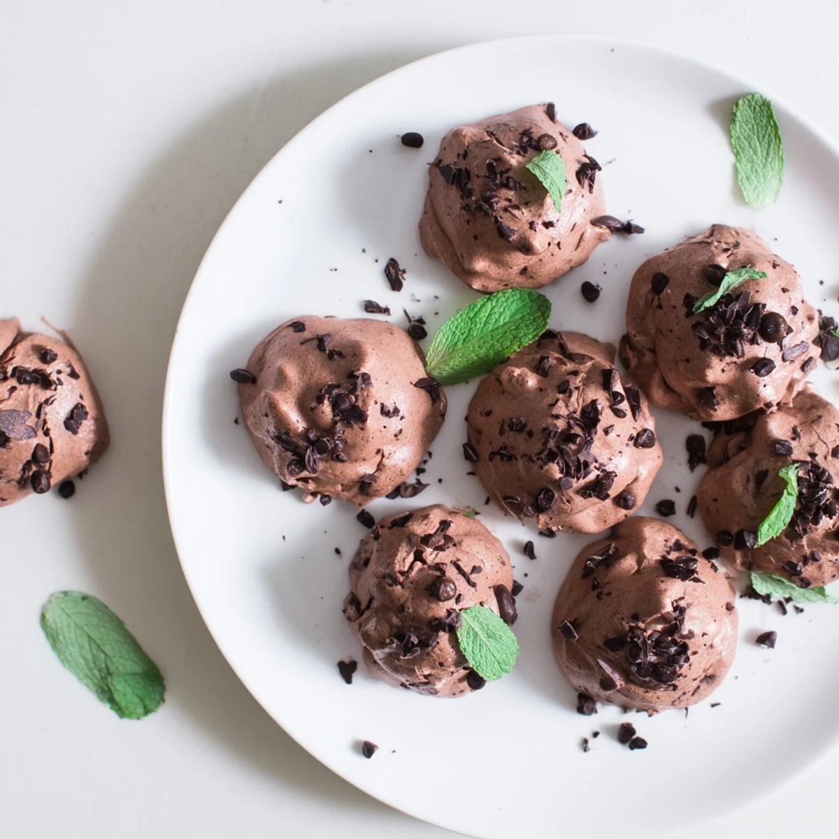 Airy dark chocolate and mint chip clouds cooling on baking sheet with chopped chocolate visible throughout