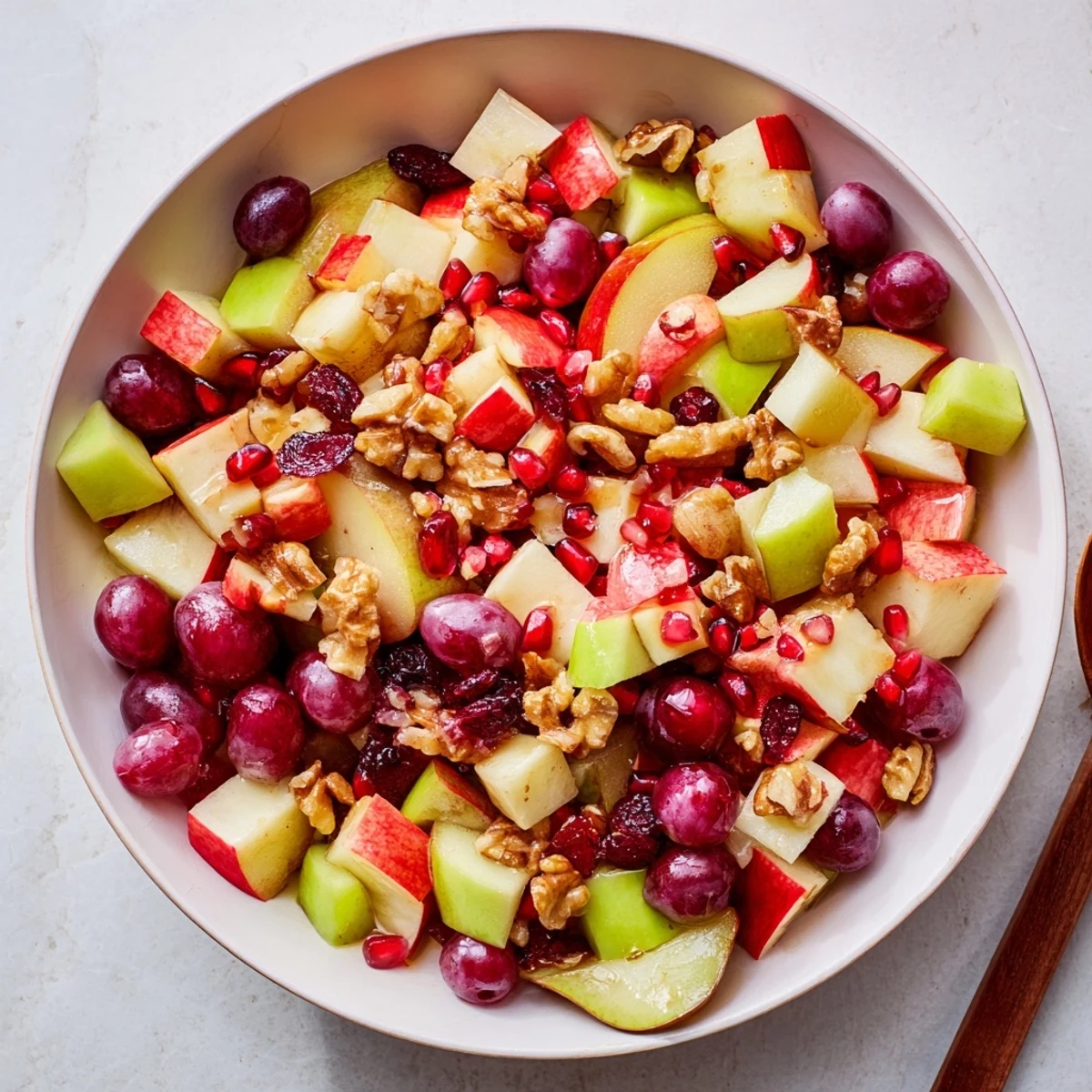 Colorful bowl of fresh minute fall fruit salad with apples, pears, and pomegranate arils drizzled with citrus-honey dressing