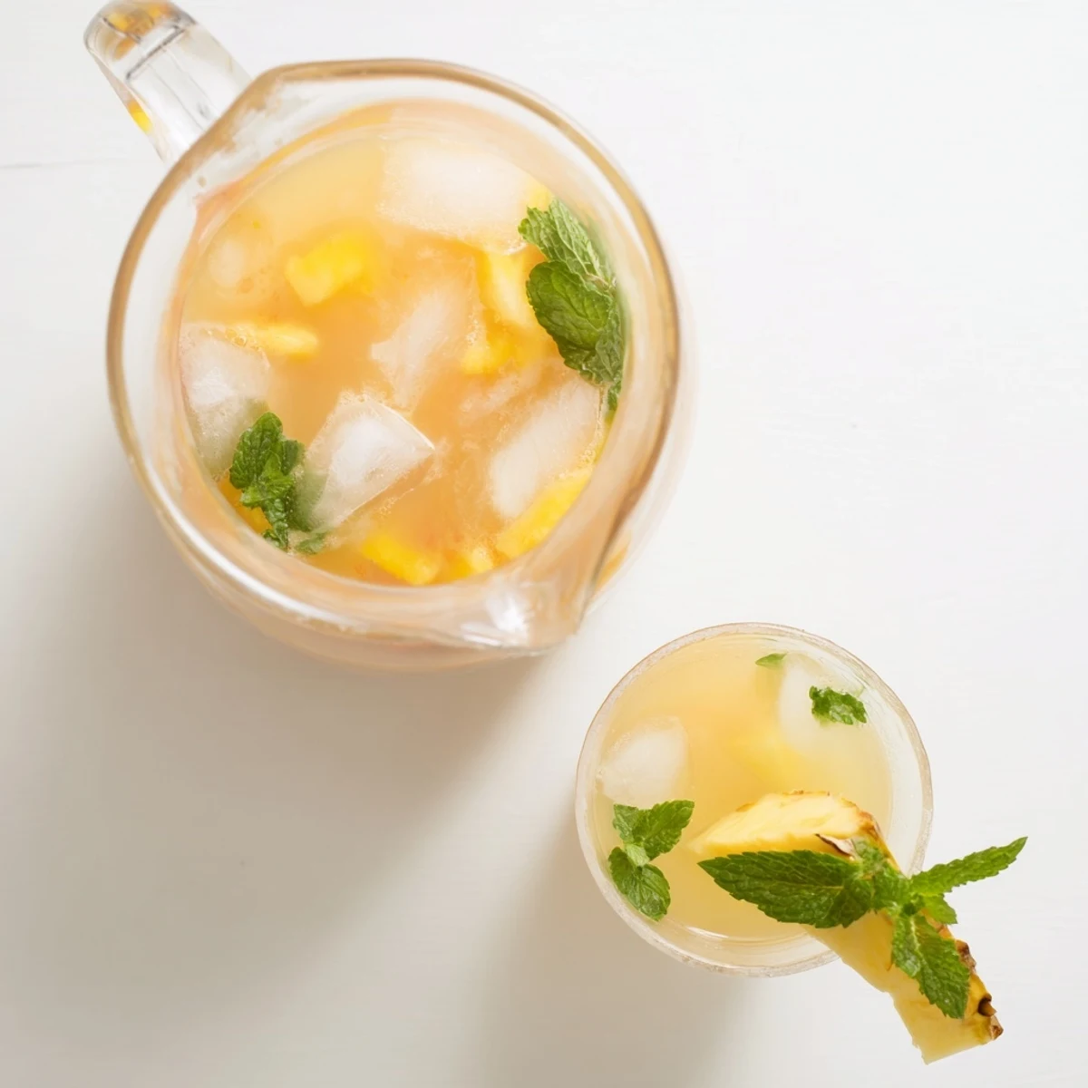 Tall glass of homemade Pineapple Peach Agua Fresca over ice topped with fresh pineapple wedge and peach slice