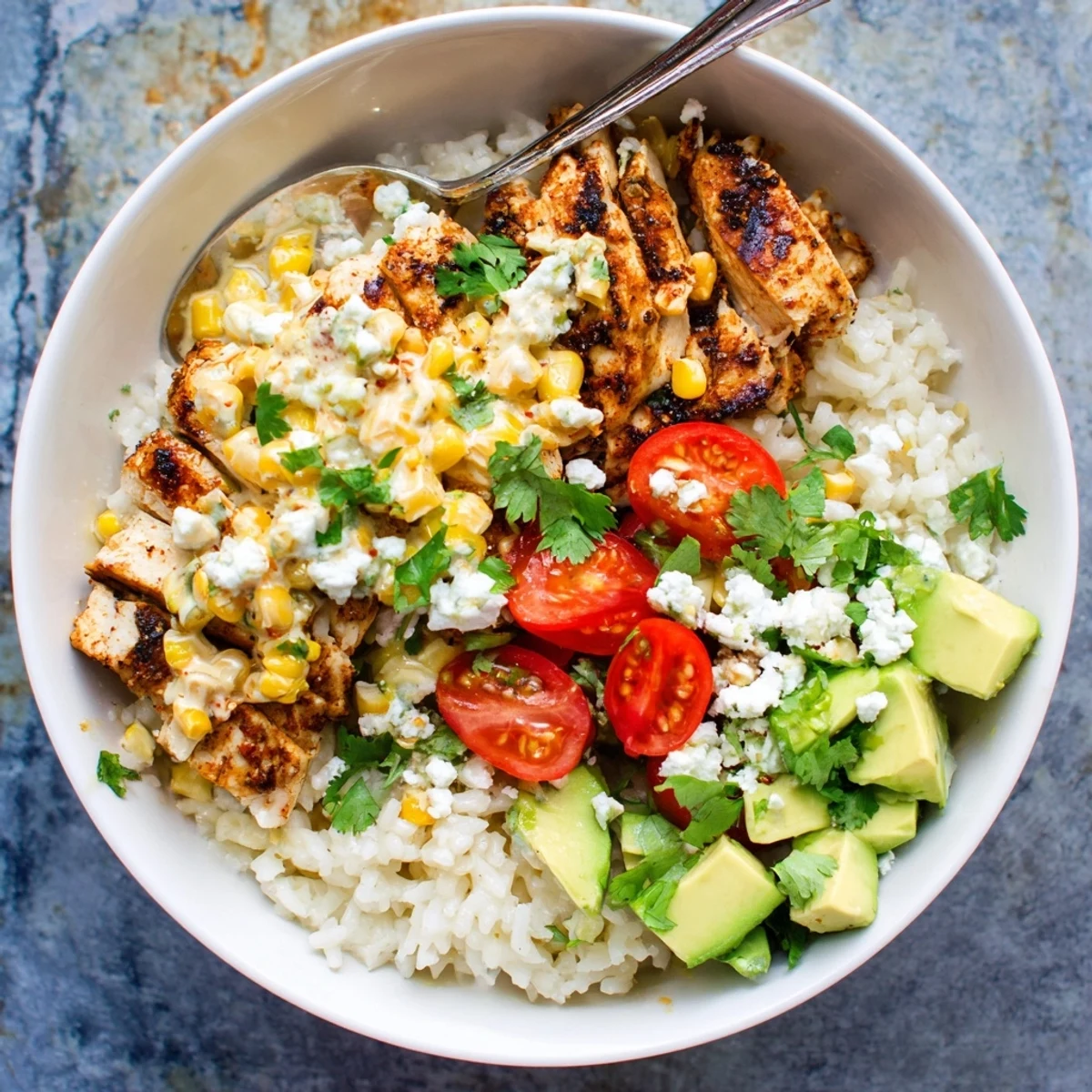 Vibrant street corn chicken and rice bowls topped with creamy cotija, avocado, and fresh cilantro