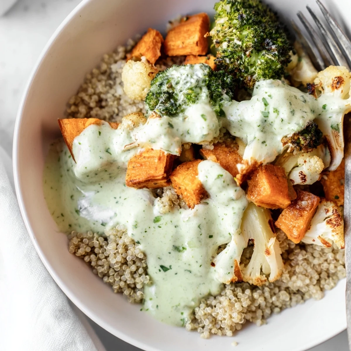 Vibrant bowl of roasted and raw vegetables smothered in green goddess dressing with pumpkin seed garnish