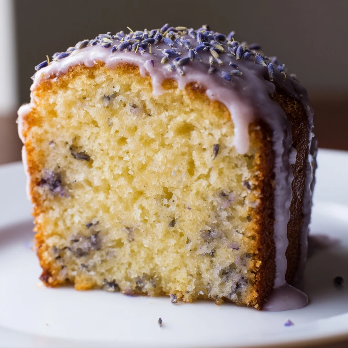 Soft lavender cake slice on a white plate with scattered purple buds