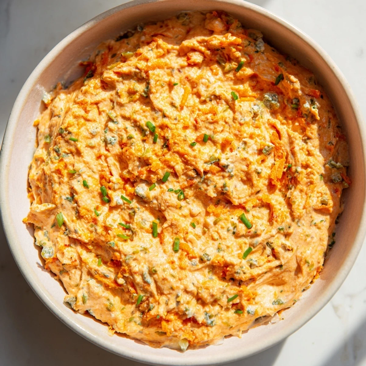 Tangy buffalo pickle dip topped with chopped chives and pickle slices ready for party snacking