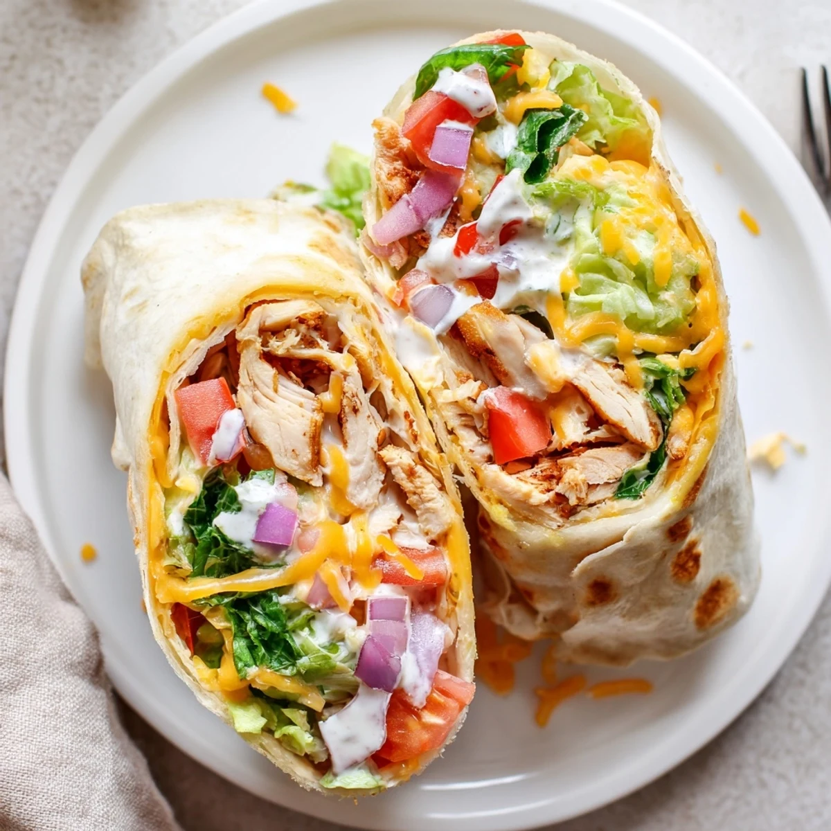 Warm Cheesy Garlic Chicken Wraps sliced in half, steam and oozing cheese