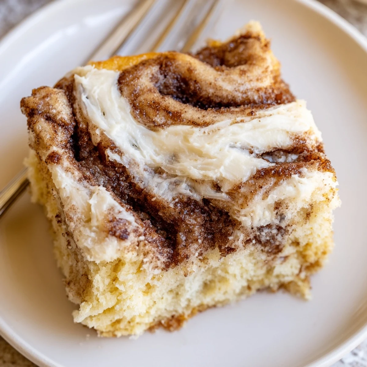 Warm Cinnamon Roll Poke Cake on plate, paired with melting vanilla ice cream